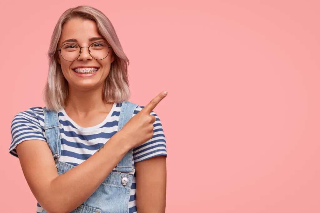 Teen with braces pointing to orthodontic care costs in Corona, CA