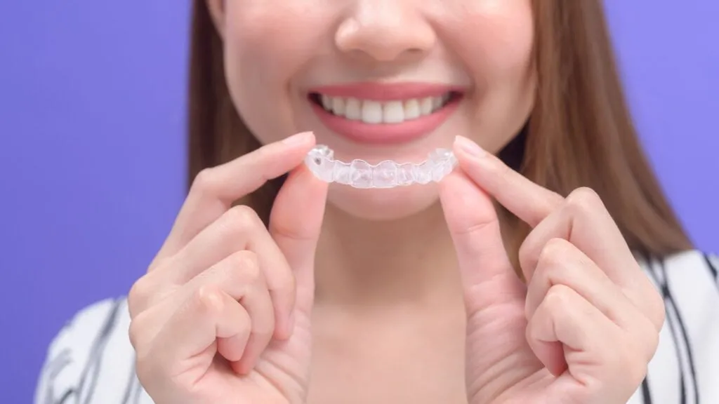 Patient holding a clear Invisalign aligner in Corona, CA