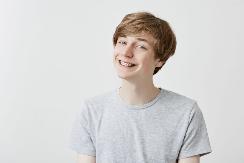 Teen boy smiling with metal braces after an adjustment appointment