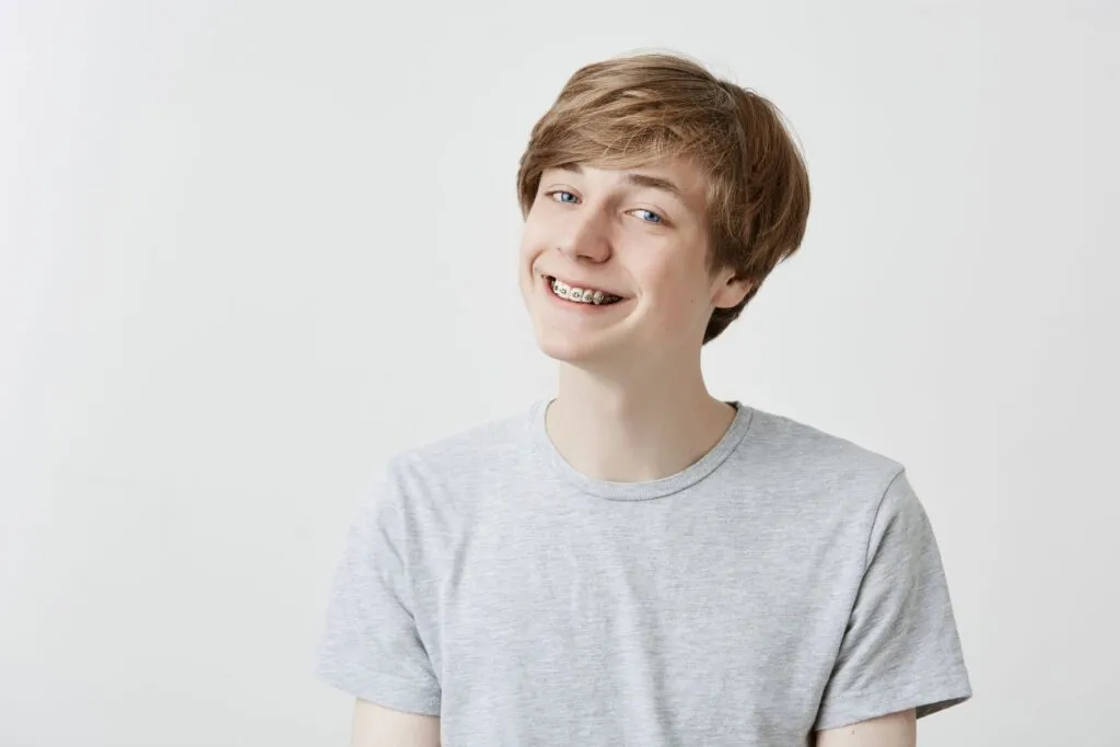 Teen boy smiling with metal braces after an adjustment appointment